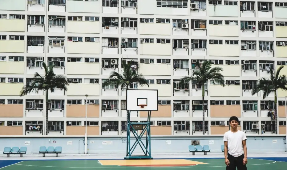 High-performance outdoor sports flooring in UAE featuring a multi-colored basketball court with blue, green, and wood-texture finishes set against a modern residential backdrop.