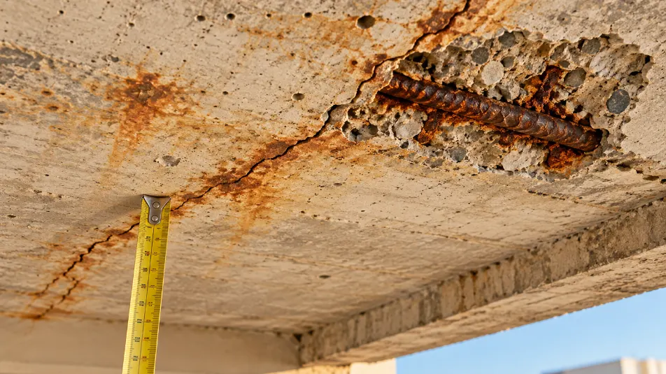 Old concrete slab with rust stains, hairline cracks and spalling caused by concrete carbonation and rebar corrosion